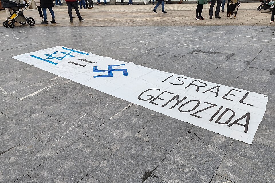 Protest banner reading Israel Genozida with an Israeli flag and swastika